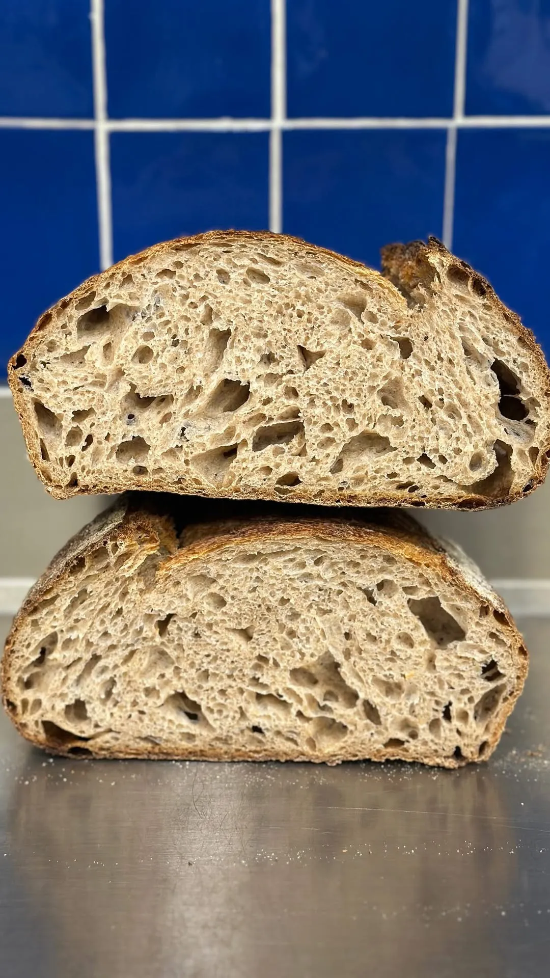 Pan de Campo de masa madre partido por la mitad, ante los azulejos azules del obrador